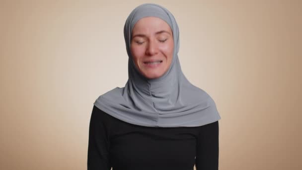 カメラでフレンドリーな笑みを浮かべてヒジャーブのイスラム教徒のビジネス女性は 正直に彼女の頭 こんにちは 挨拶ジェスチャー もてなしの表現を歓迎します アラビア人の女の子絶縁でベージュスタジオの背景 — ストック動画
