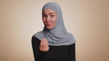Bin yıllık tesettürlü neşeli zengin kadın el hareketini boşa harcıyor ya da etrafa para saçıyor. Daha fazla bahşiş, büyük kar getiren vücut dilini hayal ediyor. Bej renkli stüdyo arka planında izole edilmiş genç Müslüman kız.
