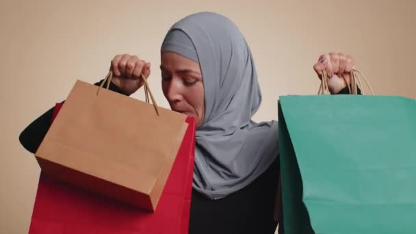 ヒジャーブ州の幸せなイスラム教徒の女性は 低価格で ブラックフライデーの休日にショッピング 購入に驚いて見て笑顔のショッピングバッグ 広告割引を示しています 若いですアラビア語女の子オンベージュ背景 — ストック動画