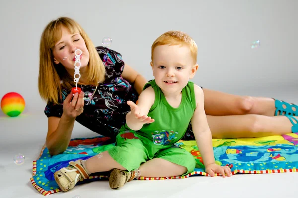 Mamá e hijo jugando con burbujas de jabón — Foto de Stock