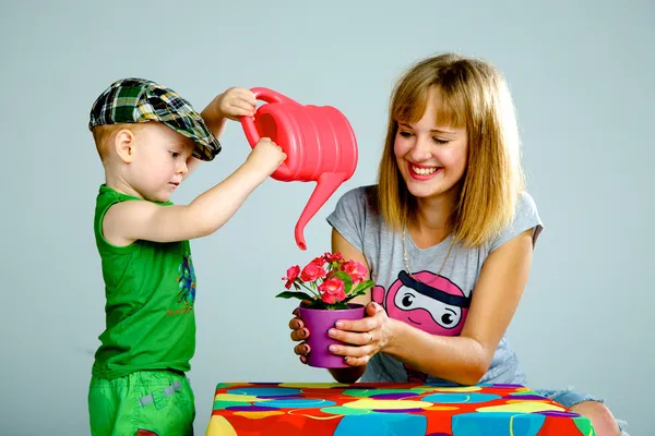 Madre e hijo regando flores con una regadera — Foto de Stock