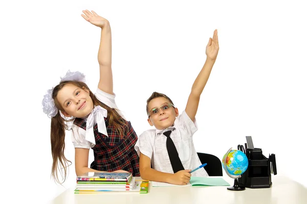 Ein Junge und ein Mädchen am Schreibtisch hoben die Hände — Stockfoto