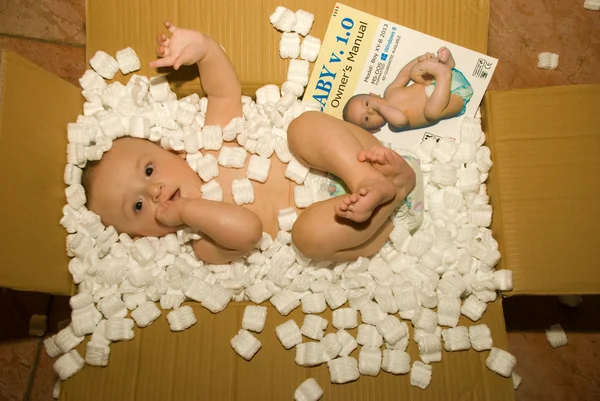 Bebê em pacote de entrega com manual de instruções — Fotografia de Stock