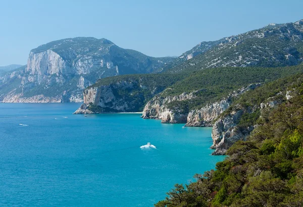 Utsikt over den populære stranden Sardinia i Cala Luna, Italia, populær destinasjon på Sardinia, krystallhav med småbåter og tåkefjell-bakgrunn i Cala Luna, sardinsk landskap – stockfoto