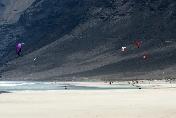 カイト サーフィン山の背景を持つ、凧のサーファー ランサローテ島 famara ビーチ カイト サーフィン ランサローテ島での会議で、夏の活動のフラグメント、ウォーター スポーツ、カイト サーフィン凧のサーファーのトレーニング、スポーツ ストック写真