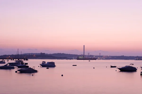 Sunrise Visa i malta, sunrise timmar med lila hav och mörka båtar i bakgrunden. Malta i soluppgång tid med båtar i havet. Malta. Sunrise timmar med fin dimma Visa. morgondimman. — Stockfoto