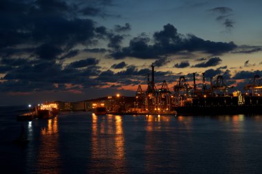Kargo alanı su ve dramatik bulutlu gökyüzü arka plan üzerine düşünceler ile gece saat on. Endüstriyel kargo bölge birzebugga, malta, koyu arka plan üzerinde. gece time.noisy endüstriyel kargo alanı.