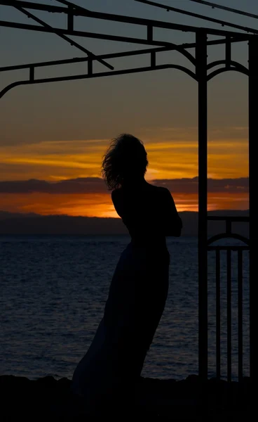 Woman silhouette in golden sunset with the sea background, dramatic sunset and alone woman, romantic mood, single alone woman in romantic atmosphere, romantic sunset,  woman in asia, summer holidays