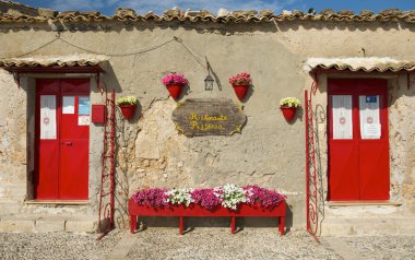 Colorful typical sardinian house with the red flowers and blue sky background, orange house fragment close up in sunny day, colorful sardinian house, nice building in Porto Torres, Sardinia, Italy, clipart