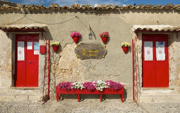 Färgglada typiska sardiska hus med röda blommor och blå himmel bakgrund, orange house fragment på nära håll i solig dag, färgglada sardiska hus, fin byggnad i porto torres, Sardinien, Italien, — Stockfoto