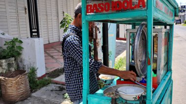 Meatball street food vendor. Asian man selling bakso by walking and pushing down the food carts, Pekalongan, December 27, 2021