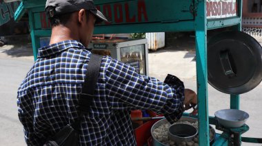 Meatball street food vendor. Asian man selling bakso by walking and pushing down the food carts, Pekalongan, December 27, 2021