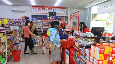 Virüs salgını sırasında alışveriş. Cerrahi maske takan insanlar süpermarketten mal alıyorlar. Aile dükkanda. Batang, 17 Ocak 2022