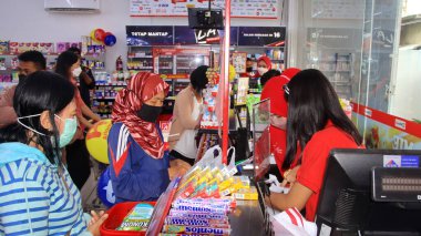 Virüs salgını sırasında alışveriş. Cerrahi maske takan insanlar süpermarketten mal alıyorlar. Aile dükkanda. Batang, 17 Ocak 2022