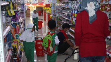 Virüs salgını sırasında alışveriş. Cerrahi maske takan insanlar süpermarketten mal alıyorlar. Aile dükkanda. Batang, 17 Ocak 2022