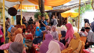 Guests enjoying a traditional wedding party, Kendal, Indonesia, 6 July, 2022