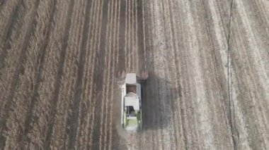 Açık havada tarlada çalışan bir mısır biçme makinesi hareket halindeyken havadan çekiliyor.