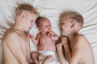 Yatakta beyaz çarşafları olan üç küçük şirin kardeş. Yüksek kalite fotoğraf