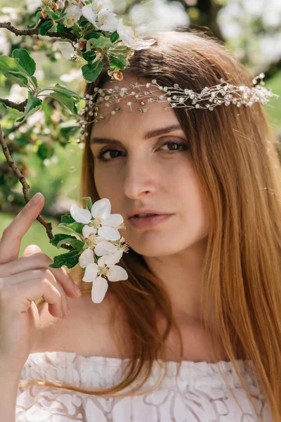 Güneşli bir bahar gününde, bir elma bahçesinde başında taç olan beyaz elbiseli güzel bir kızın portresi. Yüksek kalite fotoğraf