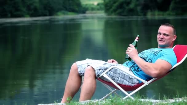 Young man relaxing in nature and drinking refreshing drink — Stock Video