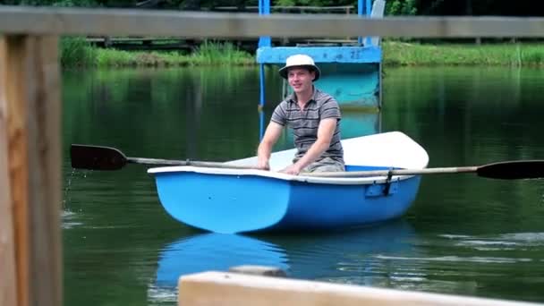 Young man on a boat preparing for fishing on a pond — Stock Video