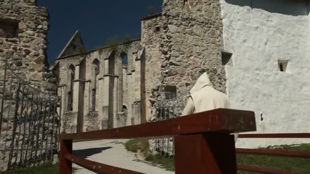 Aufnahme eines alten Klosters mit Zaun und wanderndem Mönch — Stockvideo