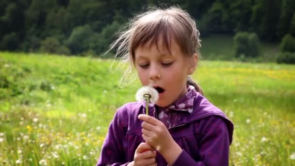 Постріл маленької дівчинки, що дме розквіт кульбаби — стокове відео