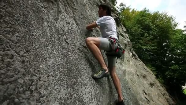 Young man rock climbing in nature shot from side — Stock Video