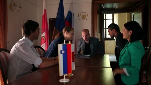 Varios empresarios sentados para una reunión en una oficina con banderas — Vídeos de Stock