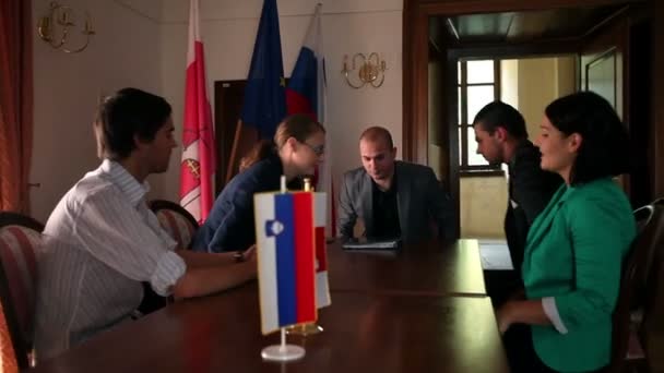 Plusieurs hommes d'affaires assis pour une réunion dans un bureau avec des drapeaux 