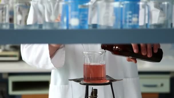 Prise de vue du jeune étudiant mélangeant du liquide sur le feu dans le cadre d'une expérience — Video