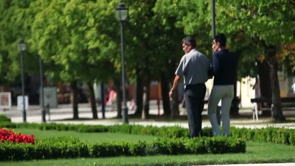 Foto de una pareja en el parque con el hotel en la espalda — Vídeo de stock