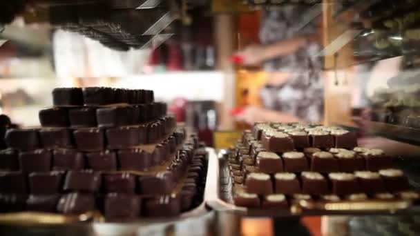 Shot van een vrouw op zoek naar chocolade pralines in schot met reflectie op showcase — Stockvideo