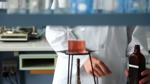 Shot of the young student mixing some liquid on the fire as a part of experiment — Stock Video