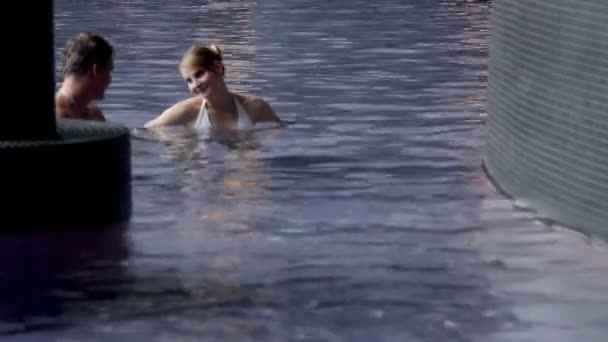 Mladý pár v bazénu čit chatování — Stock video