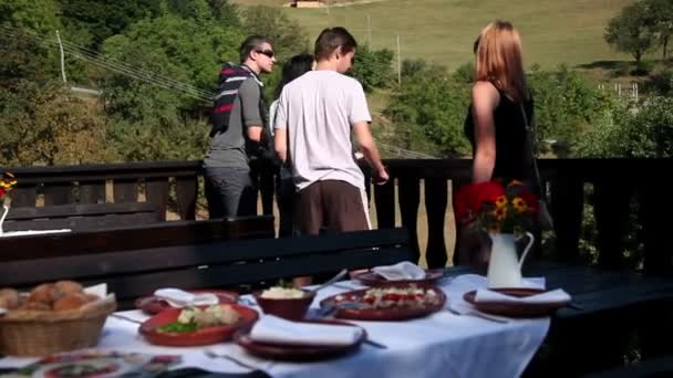 Две пары, указывающие друг на друга и смотрящие на лес перед тем, как съесть колбасу — стоковое видео