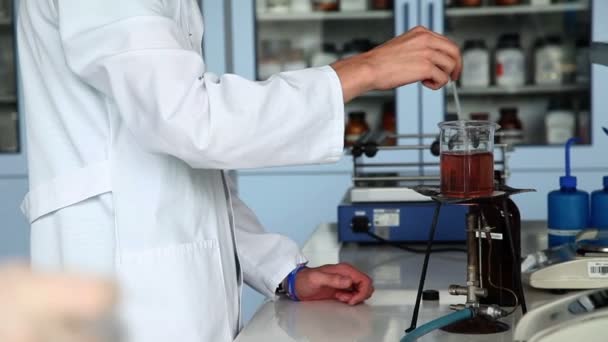 Prise de vue du jeune étudiant mélangeant du liquide sur le feu dans le cadre d'une expérience — Video