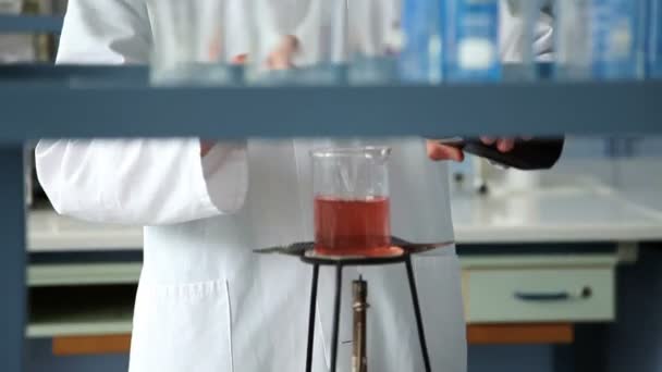 Aufnahme des jungen Studenten, der im Rahmen eines Experiments Flüssigkeit auf das Feuer mischt — Stockvideo