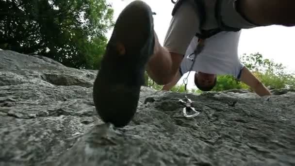 Young man rock climbing in nature shot from below — Stock Video