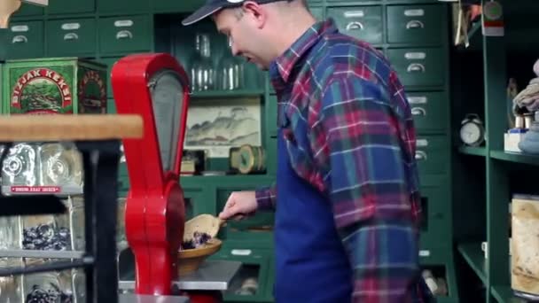 Shot of a young seller who is weighting candies in an old, retro shop — Stock Video