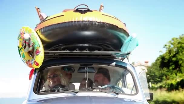 Большая семья едет на летний отдых на маленькой машине — стоковое видео