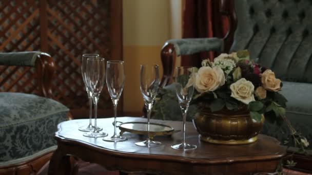 Primer plano de una mesa a la antigua en un restaurante con un ramo y glasos para champán — Vídeo de stock