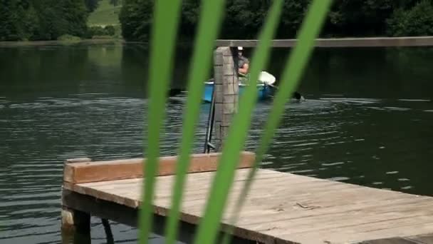 Joven en un barco preparándose para pescar en un lago — Vídeos de Stock