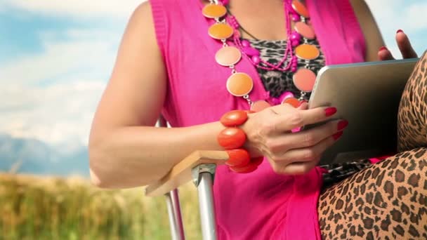 Vrouw zitten in de natuur en typig op een tablet pc — Stockvideo