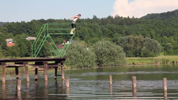Hombre saltando desde el muelle en el lago — Vídeos de Stock