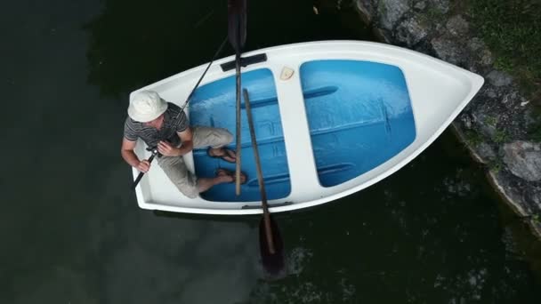 Молодий чоловік ловить рибу з човна, знятого зверху — стокове відео