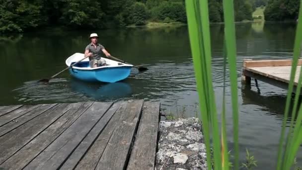 Молодой человек готовится к рыбалке на лодке — стоковое видео