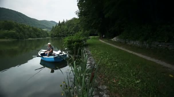 Joven pescador pescando desde el barco en el estanque — Vídeos de Stock