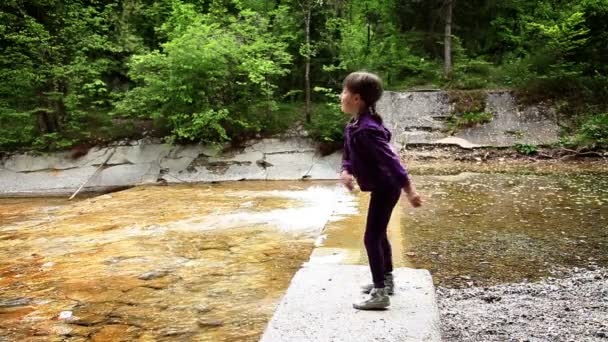 Выстрел маленькой девочки, бросающей камни в реку — стоковое видео