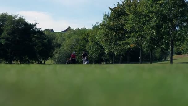 Tourné d'un coouple qui va sur l'autre terrain de golf prenant soin de tout l'équipement de golf — Video